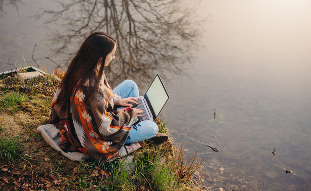 girl writing near lake